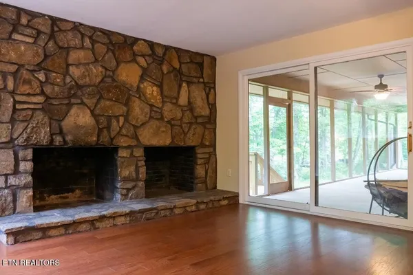 an empty room with wooden floor and windows with curtains