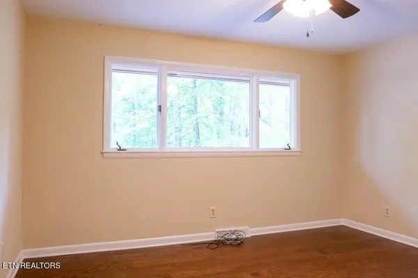 a view of an empty room with wooden floor and a window