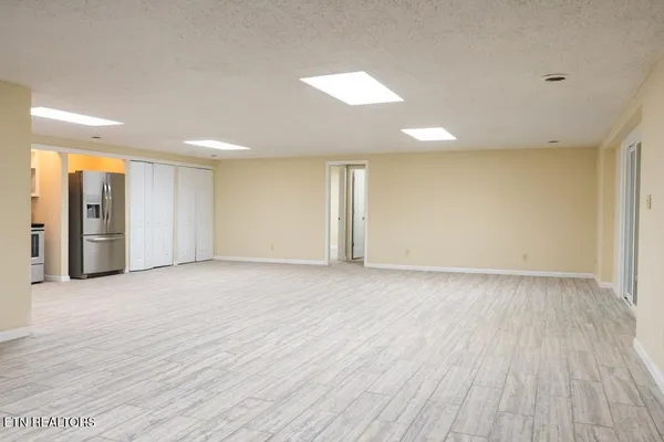 a view of an empty room with wooden floor and a window