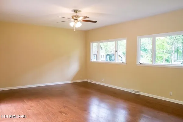 an empty room with wooden floor and windows