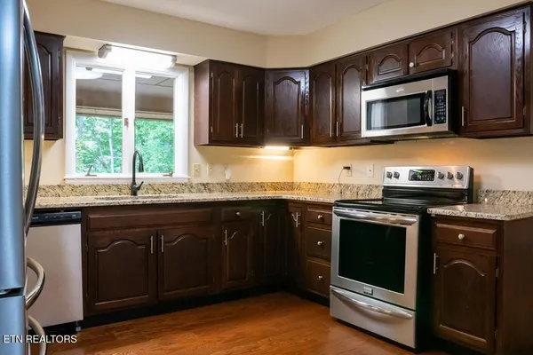 a kitchen with granite countertop a stove a sink and a microwave
