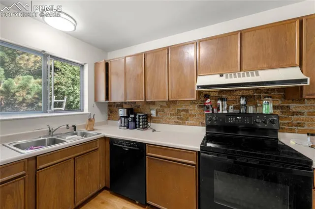 a kitchen with kitchen island granite countertop a sink cabinets stainless steel appliances and a large window