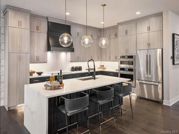 a kitchen with stainless steel appliances granite countertop a sink a stove a refrigerator and island with wooden floor