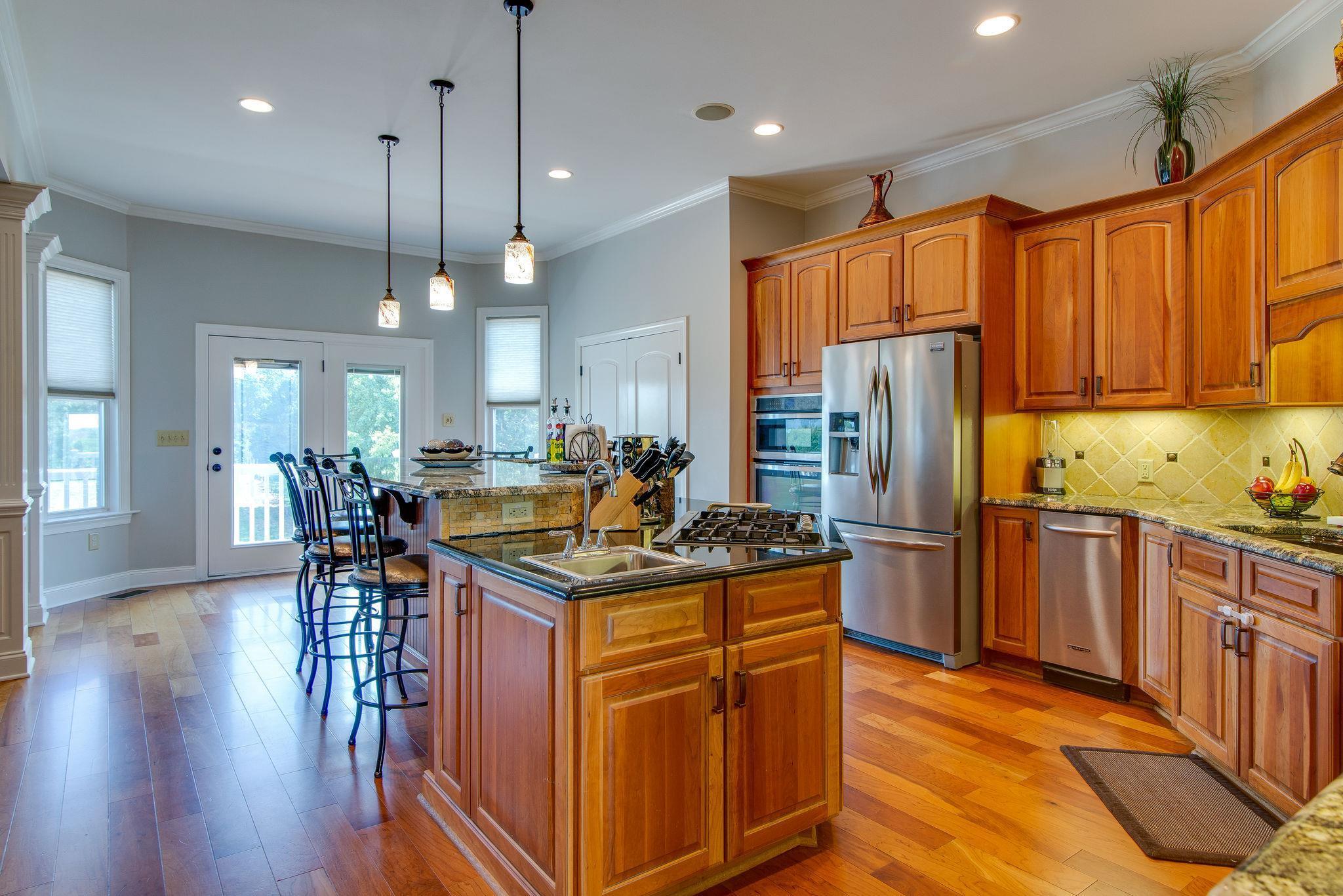6263 Beckwith Road Mount Juliet, TN 37122 - Photo 3 of 30 a kitchen with stainless steel appliances granite countertop a refrigerator a sink dishwasher a stove and a dining table with wooden floor