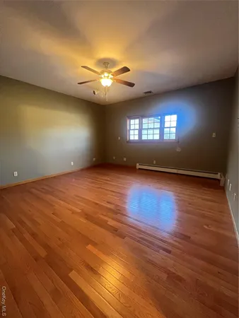 an empty room with wooden floor chandelier and glass door
