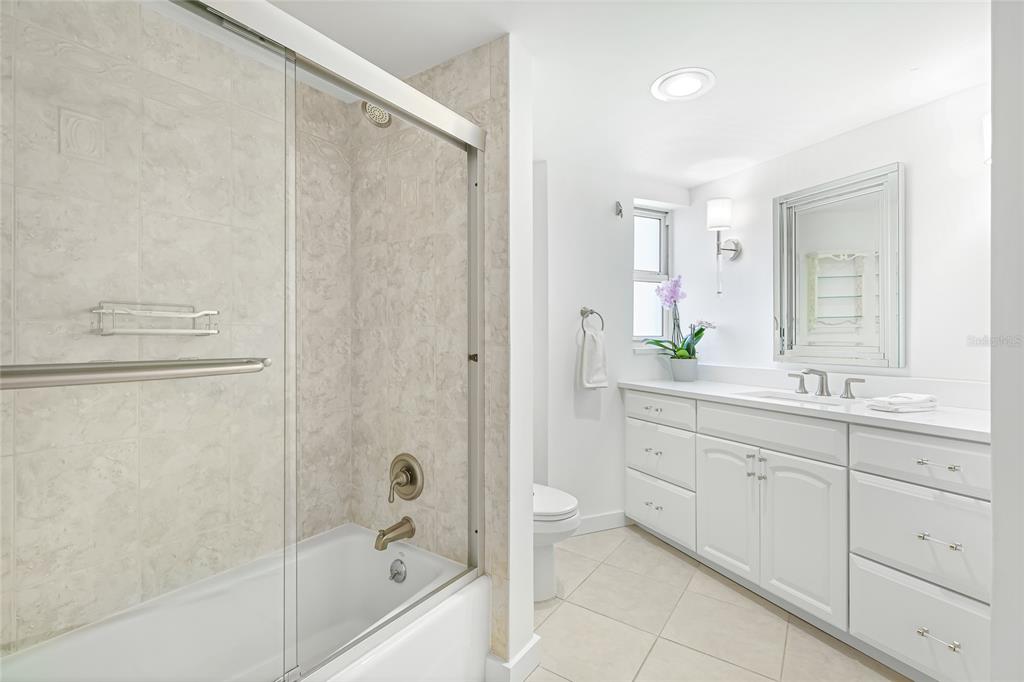 435 South Gulfstream Avenue, Unit 1004 Sarasota, FL 34236 - Photo 24 of 37 a bathroom with a granite countertop sink a mirror a bathtub and shower