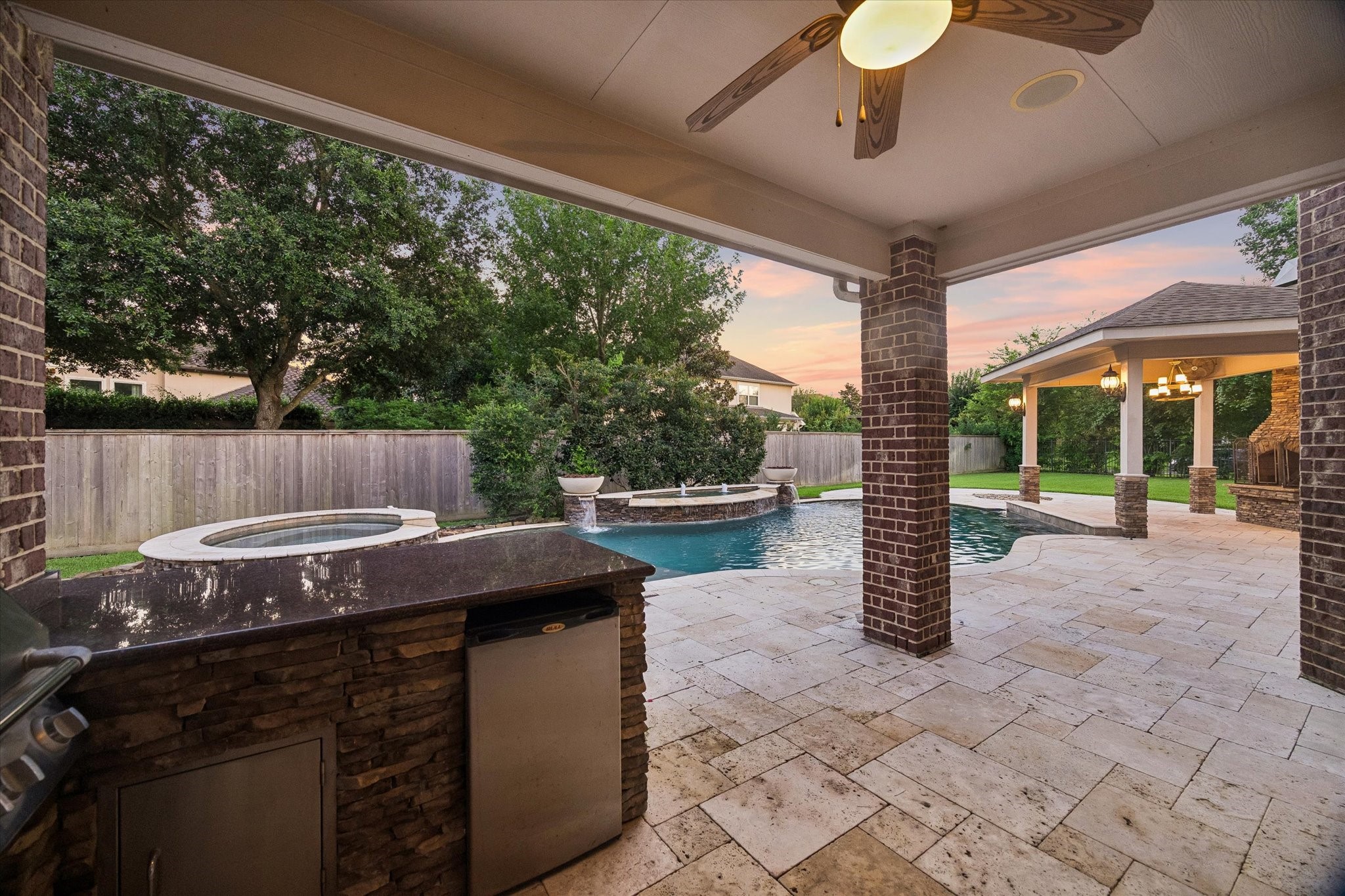 35 North Fremont Ridge Loop Spring, TX 77389 - Photo 29 of 37 Beautiful outdoor living space featuring a covered outdoor kitchen, travertine flooring, resort-style pool and spa, and generous entertaining areas. Designed for memorable gatherings with family and friends, this backyard oasis is ready to be enjoyed all summer long and beyond.