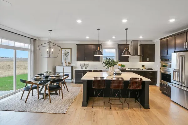 a kitchen with stainless steel appliances kitchen island granite countertop a table chairs sink and cabinets