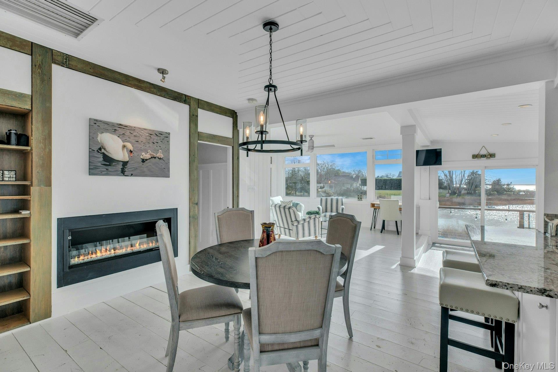 7 Springville Circle Hampton Bays, NY 11946 - Photo 13 of 43 Dining area with a glass covered fireplace, wood ceiling, light wood-style floors, a chandelier, and built in features
