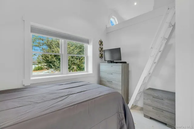 a bedroom with a bed a flat tv screen and a fireplace