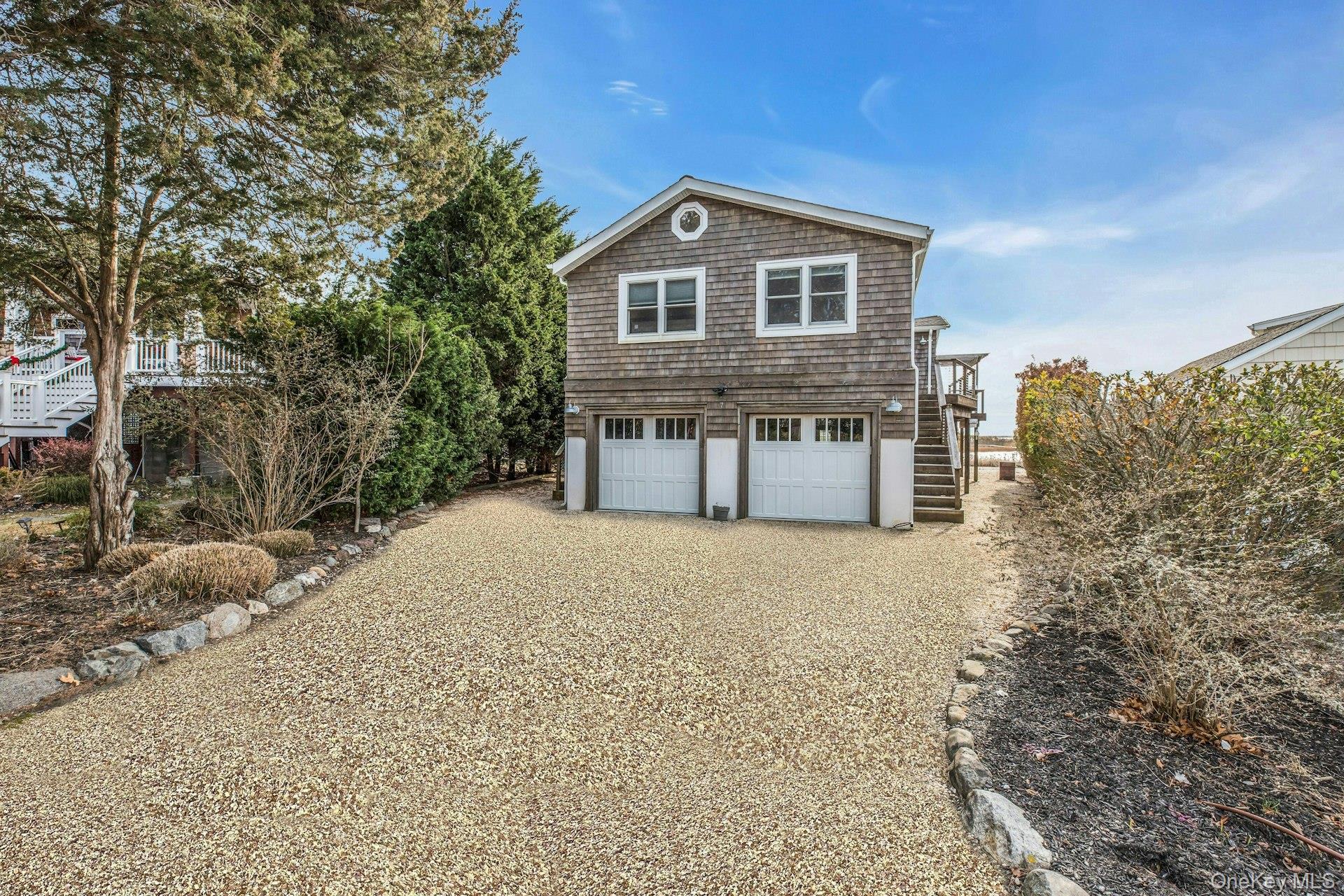 7 Springville Circle Hampton Bays, NY 11946 - Photo 27 of 43 View of property exterior featuring stairway, gravel driveway, and a deck