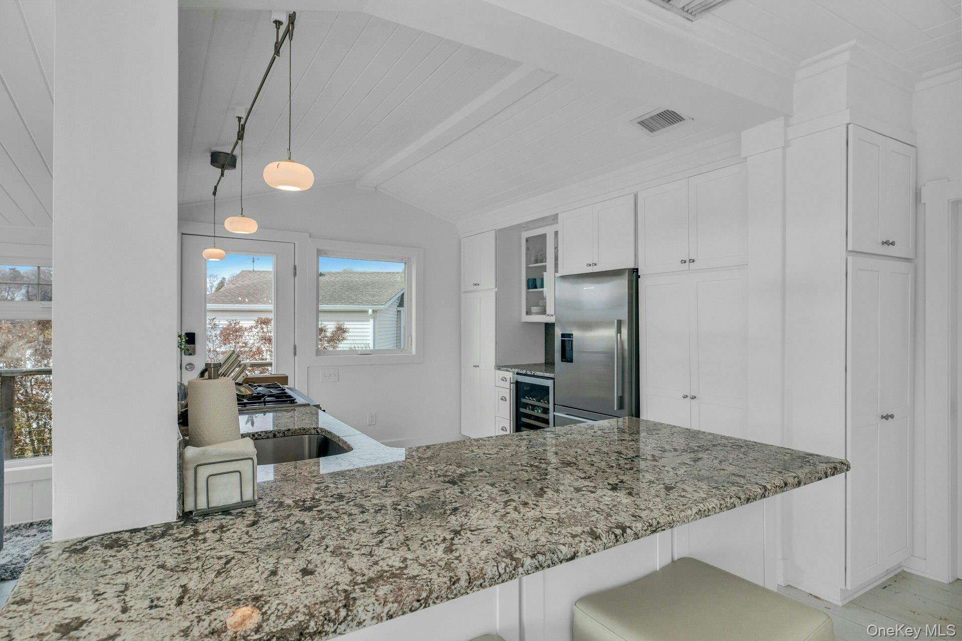 7 Springville Circle Hampton Bays, NY 11946 - Photo 10 of 43 Kitchen featuring white cabinets, light stone counters, decorative light fixtures, glass insert cabinets, and stainless steel fridge with ice dispenser