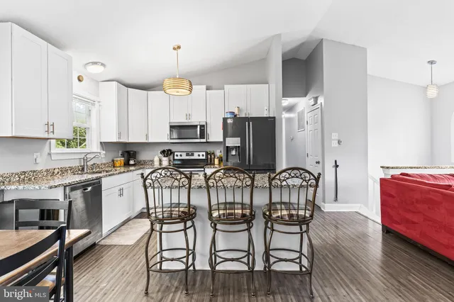 a kitchen with stainless steel appliances a dining table chairs microwave and sink
