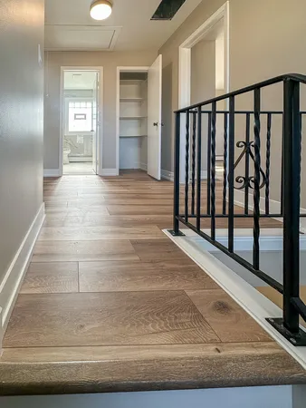 a view of a hallway with wooden floor and staircase