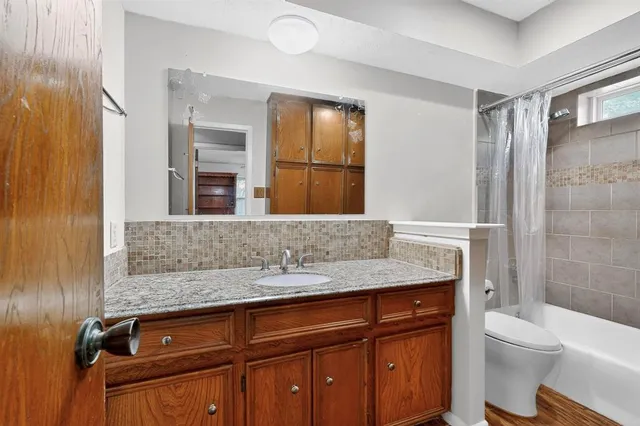 a bathroom with a granite countertop sink a toilet a mirror and shower