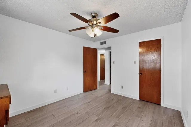 an empty room with wooden floor and ceiling fan