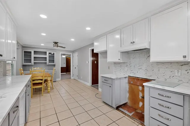a kitchen with white cabinets and chairs