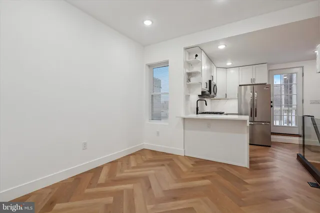 a view of a kitchen with refrigerator and white cabinets