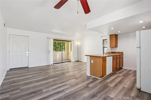 a view of kitchen and empty room with wooden floor