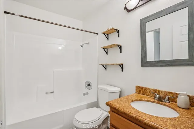 a bathroom with a granite countertop sink toilet a mirror and shower