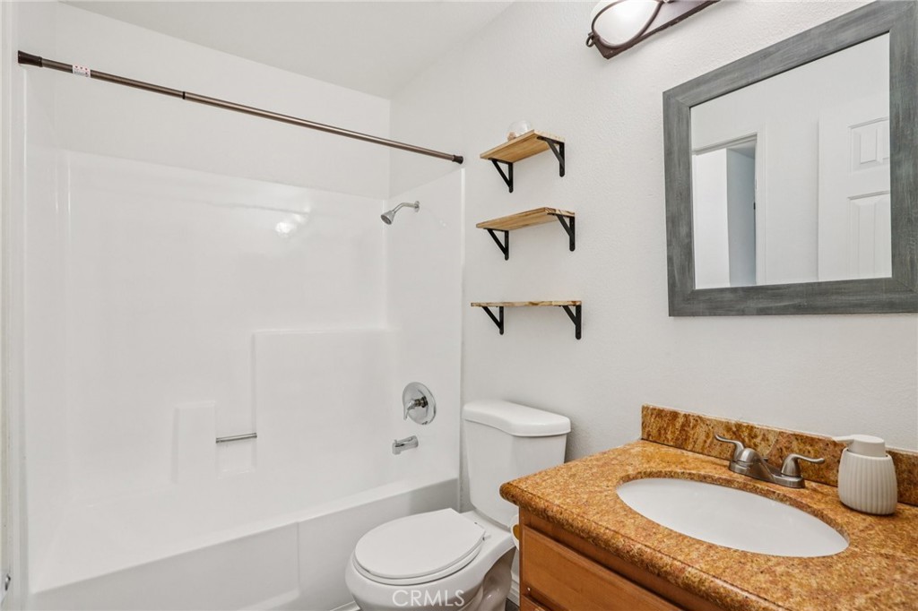 1142 West Blaine Street, Unit 201 Riverside, CA 92507 - Photo 19 of 24 a bathroom with a granite countertop sink toilet a mirror and shower