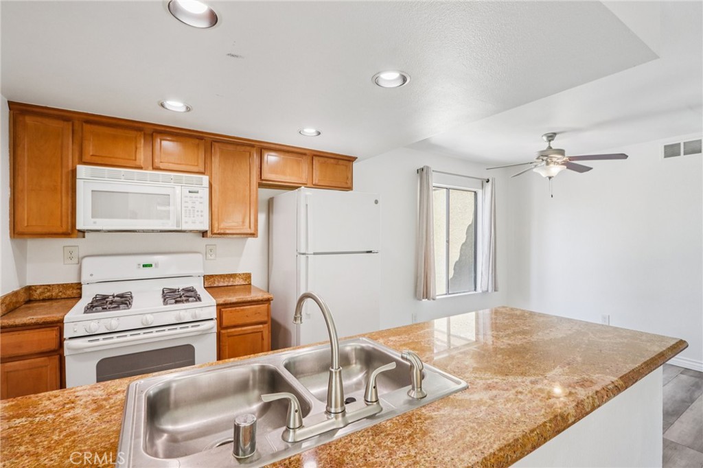 1142 West Blaine Street, Unit 201 Riverside, CA 92507 - Photo 8 of 24 a kitchen with a stove a sink dishwasher and wooden cabinets with a granite countertops