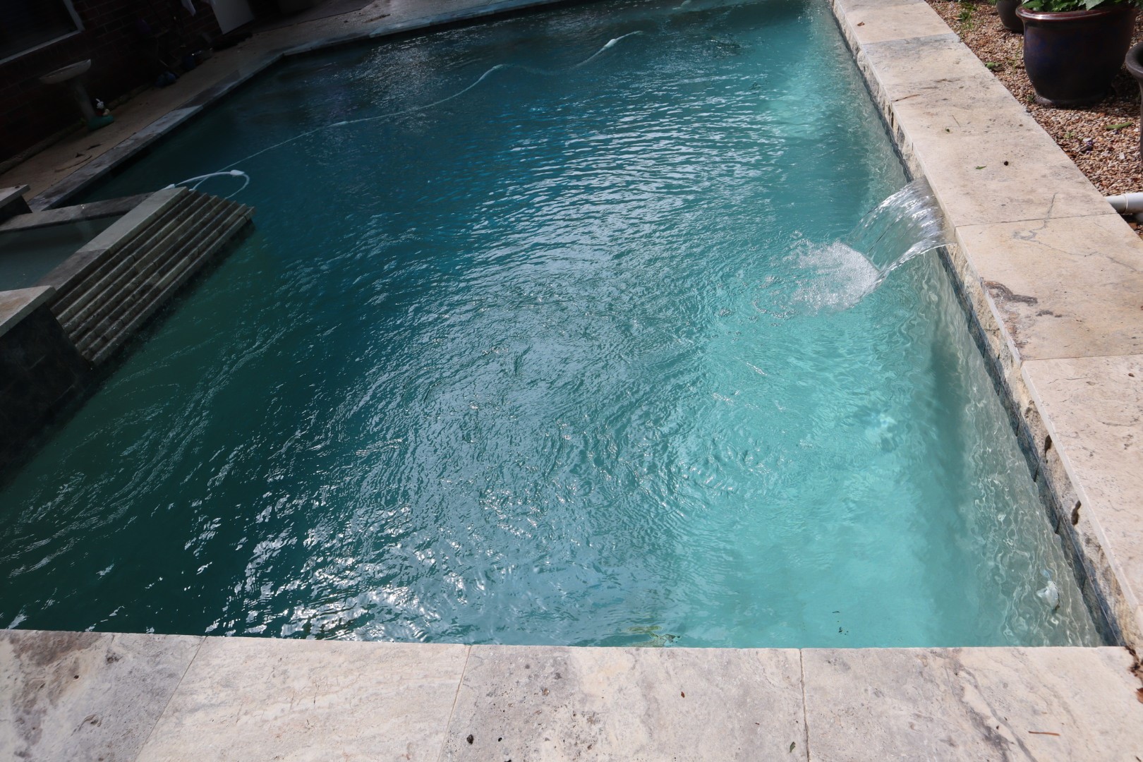19114 Emory Trail Spring, TX 77388 - Photo 31 of 32 Relax in your backyard pool with clear water, surrounded by a stone deck. The pool features a small waterspout and steps leading into the water, ideal for relaxation and leisure activities.