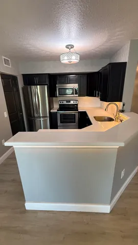 a view of kitchen with microwave and refrigerator