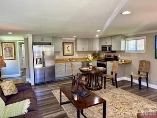 a living room with stainless steel appliances furniture a dining table and kitchen view
