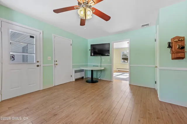 a view of an empty room with a window and wooden floor