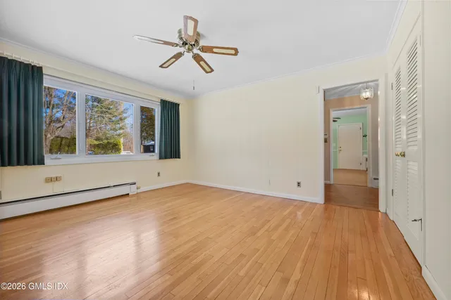 a view of an empty room with a window and wooden floor