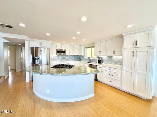 3521 Sunset Lane Oxnard, CA 93035 - Photo 17 of 37 a kitchen with stainless steel appliances granite countertop a stove top oven a refrigerator and white cabinets with wooden floor