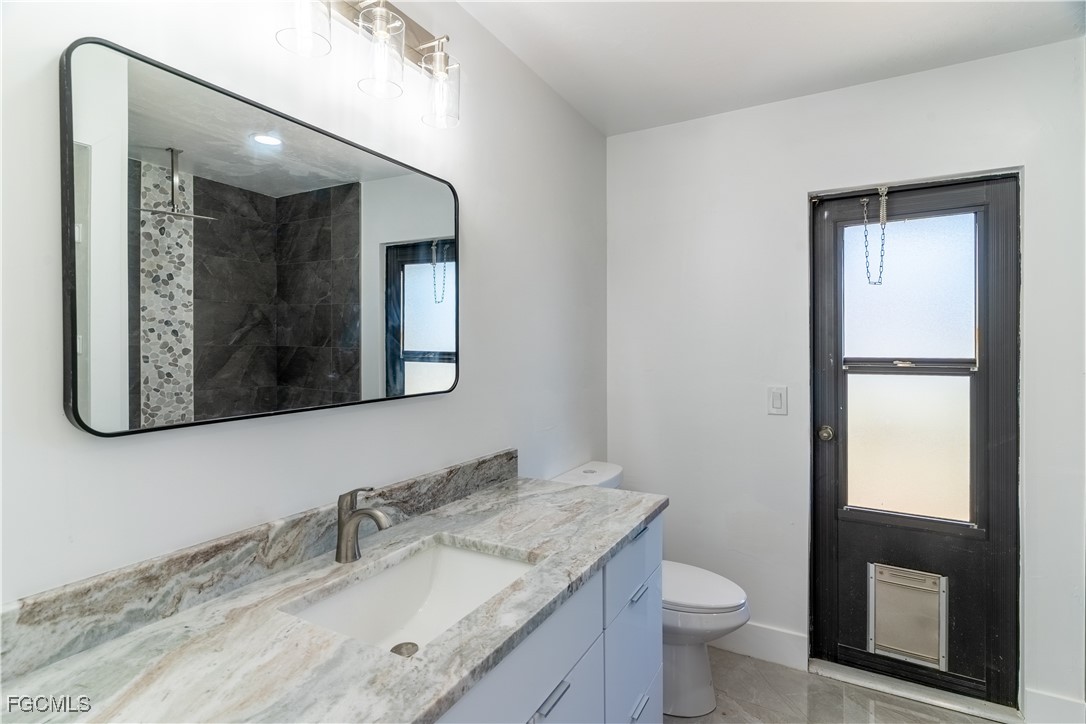 720 Chavers Street East Lehigh Acres, FL 33974 - Photo 11 of 35 a bathroom with a granite countertop sink mirror vanity and toilet