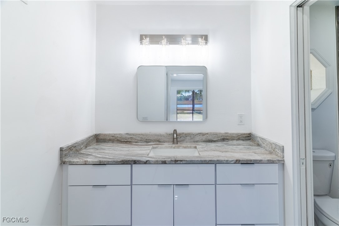 720 Chavers Street East Lehigh Acres, FL 33974 - Photo 7 of 35 a bathroom with a granite countertop sink and a mirror
