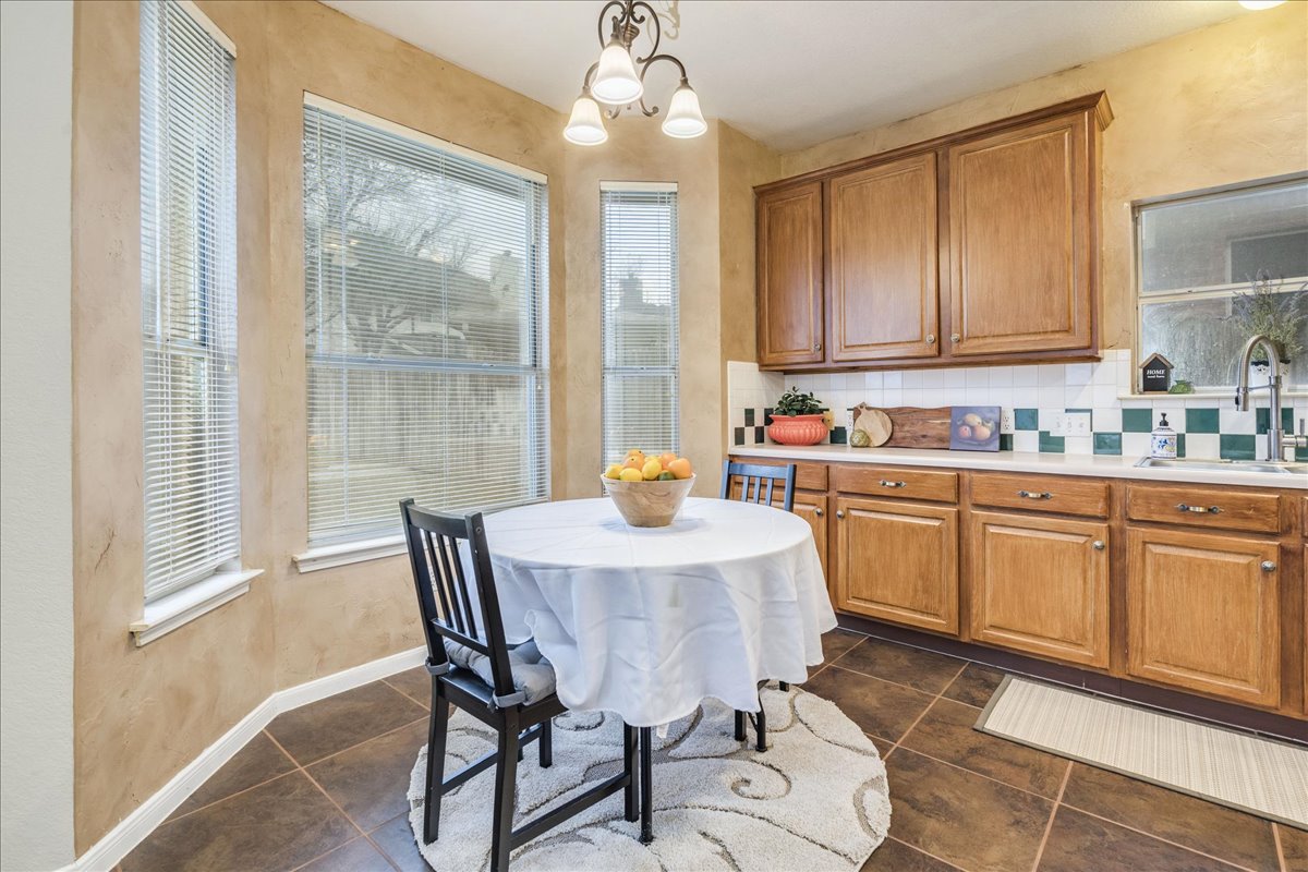1706 Apache Trail Round Rock, TX 78665 - Photo 10 of 38 Kitchen featuring wood finish cabinets, light countertops, tasteful backsplash, a chandelier, and a textured wall