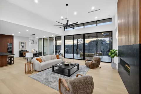 a living room with furniture ceiling fan and a large window