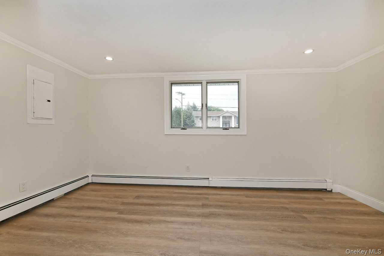 107 Beverly Road Massapequa, NY 11758 - Photo 21 of 41 a view of an empty room with wooden floor and a window