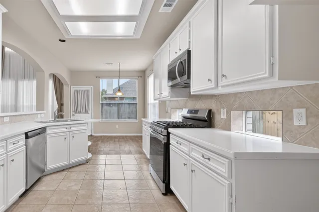 a kitchen with stainless steel appliances granite countertop a sink and dishwasher a stove top oven with white cabinets