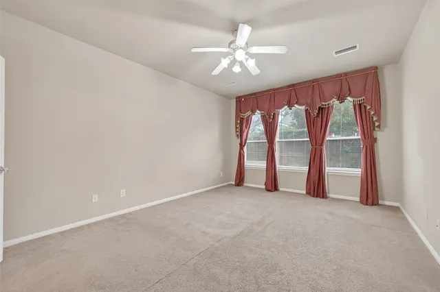 an empty room with windows and chandelier fan