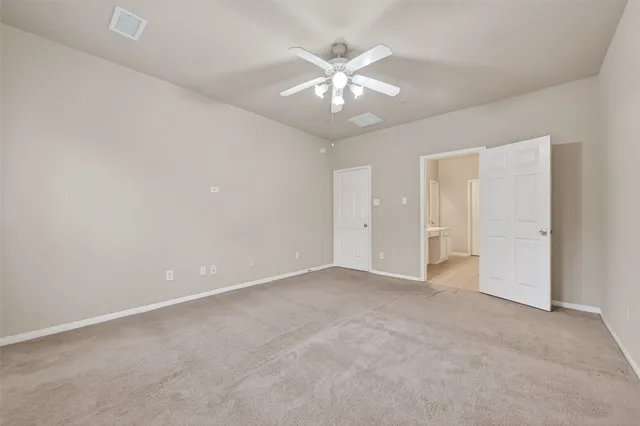 an empty room with chandelier fan and closet area