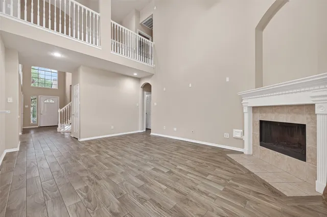 a view of an empty room with wooden floor and a fireplace