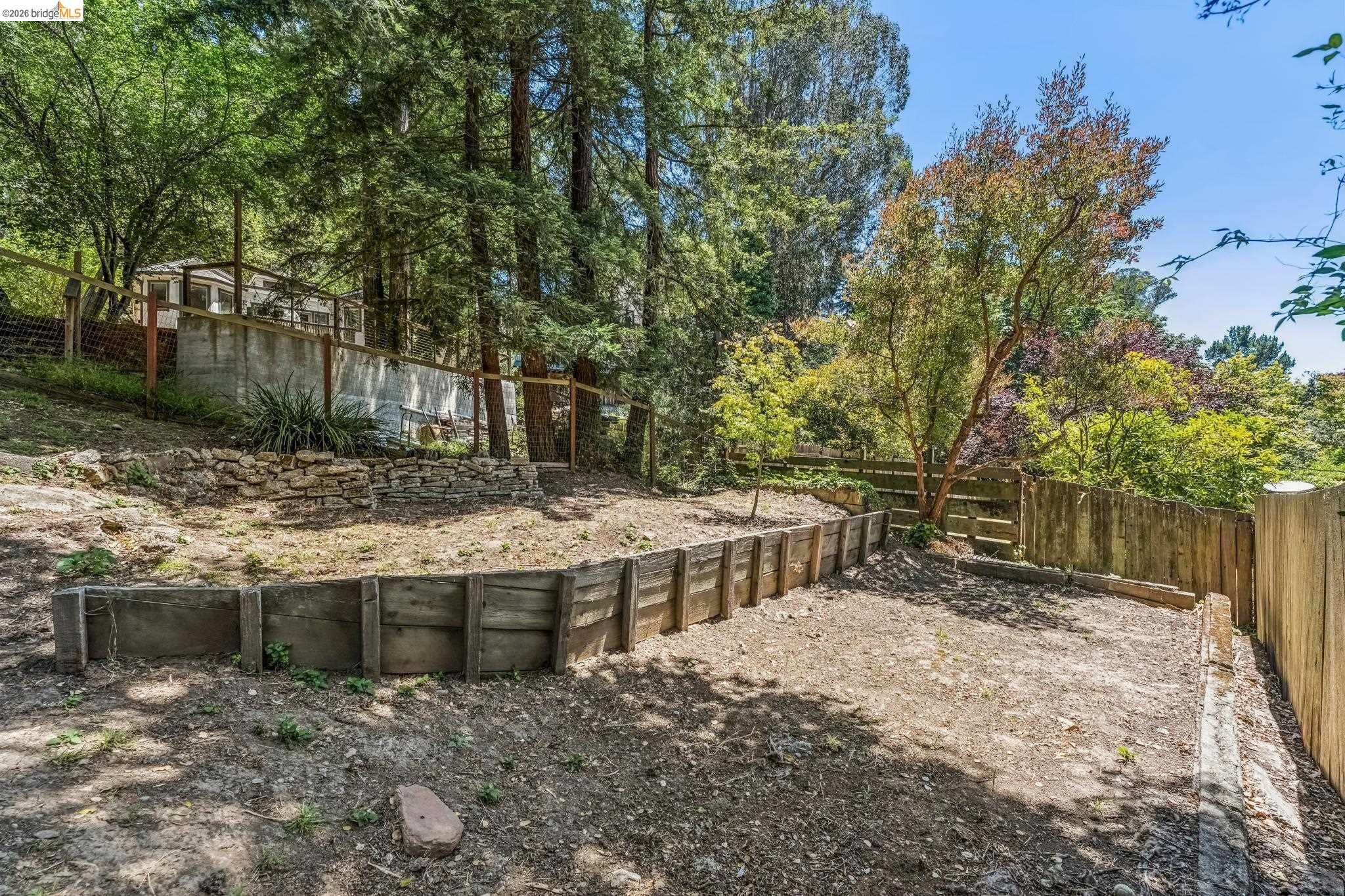 6645 Heather Ridge Way Oakland, CA 94611 - Photo 57 of 61 Tiered backyard featuring a wooden retaining wall, natural wood fencing, and mature trees
