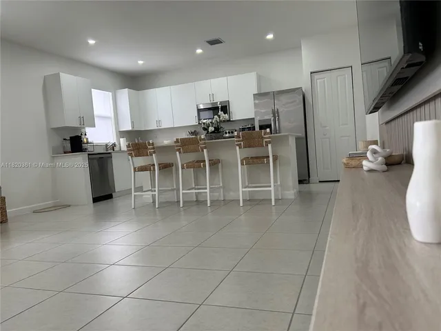 a kitchen with stainless steel appliances granite countertop a refrigerator a stove a sink and white cabinets