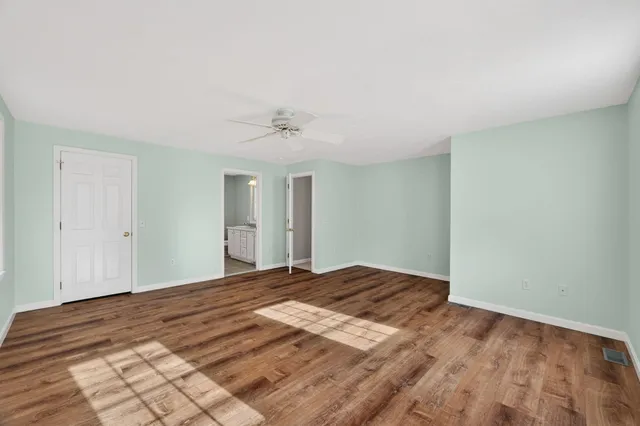 a view of a big room with wooden floor and chandelier fan