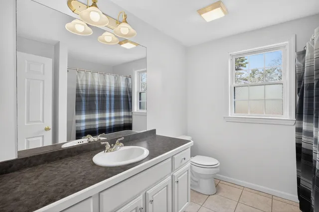 a bathroom with a granite countertop sink a toilet and a mirror