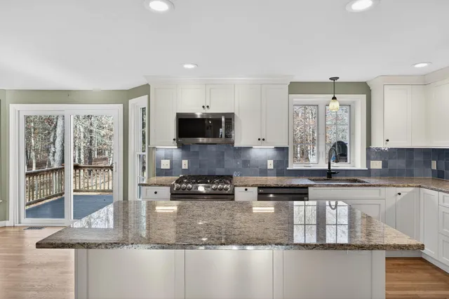 a kitchen with kitchen island granite countertop a sink counter top space appliances and cabinets