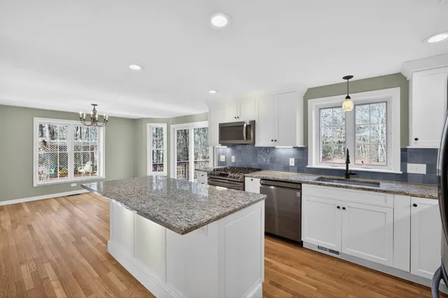 a kitchen with stainless steel appliances granite countertop hardwood floor sink stove and wooden cabinets
