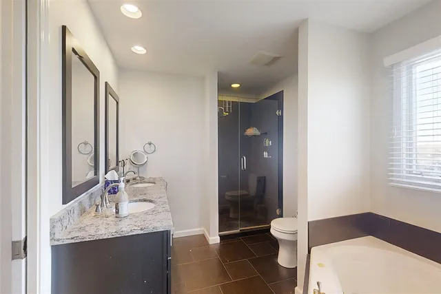 a spacious bathroom with a granite countertop sink a toilet and a mirror