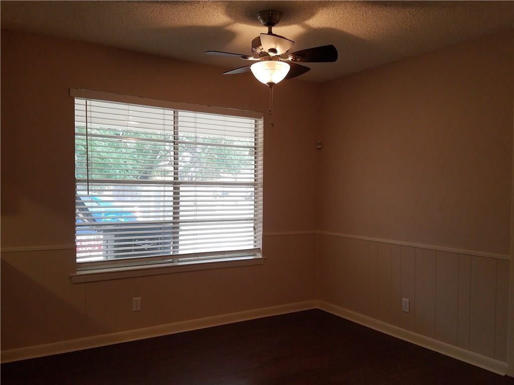 6919 West Cleburne Road Fort Worth, TX 76133 - Photo 9 of 15 Room featuring a large window with white blinds, dark wood-finish flooring, and a ceiling fan with integrated lighting