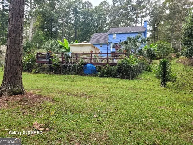 a backyard of a house with plants and large trees